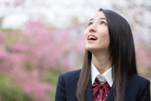 桜を見上げる女子高校生