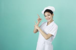 両手でポイントポーズをする笑顔の女性看護師さん