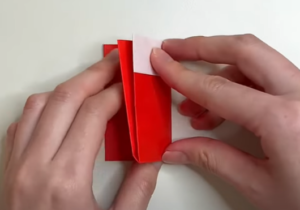 折り紙の2センチ折った側を上にして裏返しにしたら、両側を中央に向けて折る。その状態で上に向けて半分に折る。さらに横に向けて半分に折る