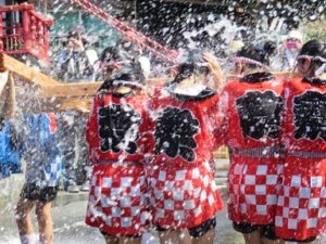 お祭りで神輿を担ぐ女性たちと打ち水