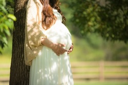 公園で木に寄りかかる妊婦さん