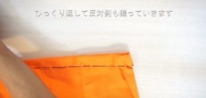 オレンジの布を手縫いで縫う