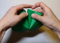 緑の折り紙を折り目に沿って折る