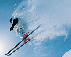 雪を舞い上げてスキーをする男性