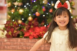クリスマスツリーと大きなリボンを付けた女の子