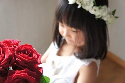 花かんむりををつけた女の子と赤いバラの花