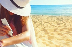 海岸で日焼け止めを塗る女性